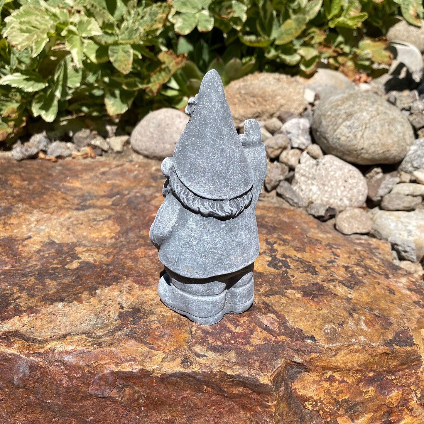 A cute garden gnome holding a shovel, perfect for yard and patio decor