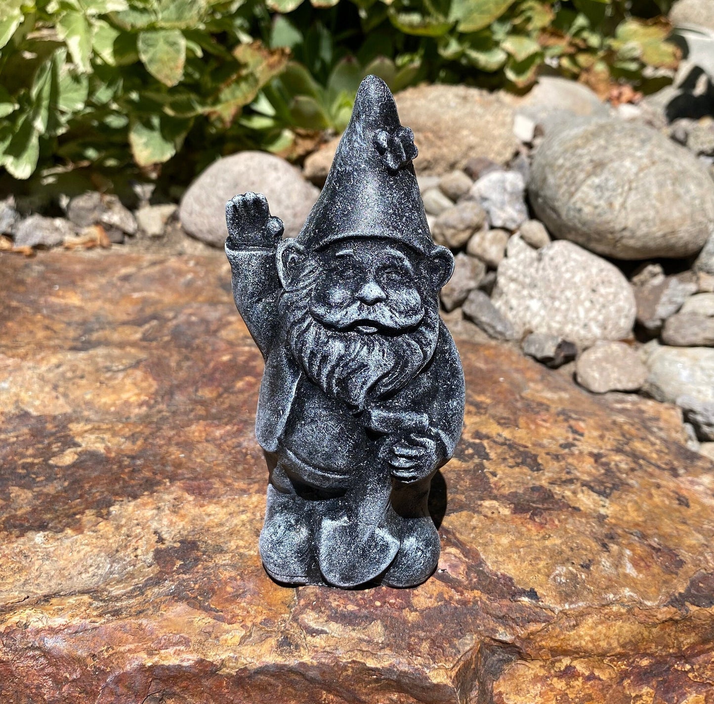 A cute garden gnome holding a shovel, perfect for yard and patio decor
