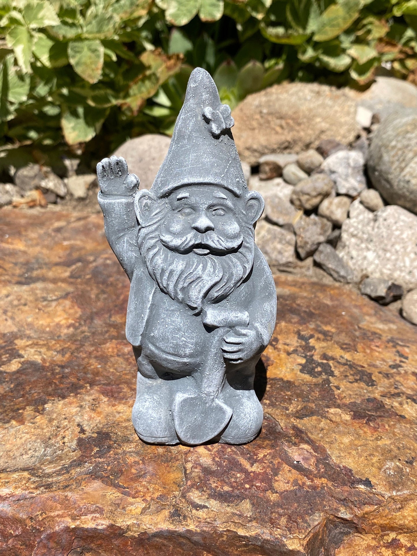A cute garden gnome holding a shovel, perfect for yard and patio decor