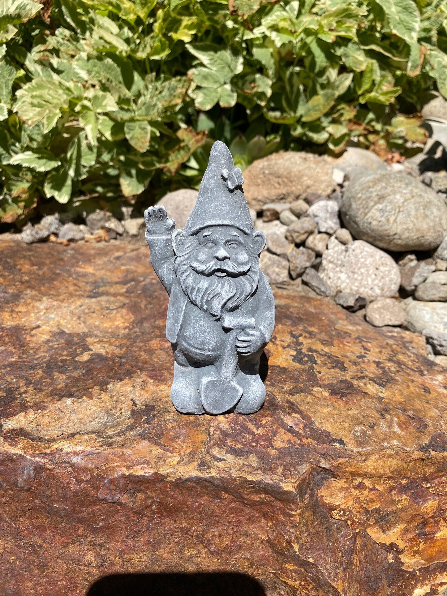 A cute garden gnome holding a shovel, perfect for yard and patio decor