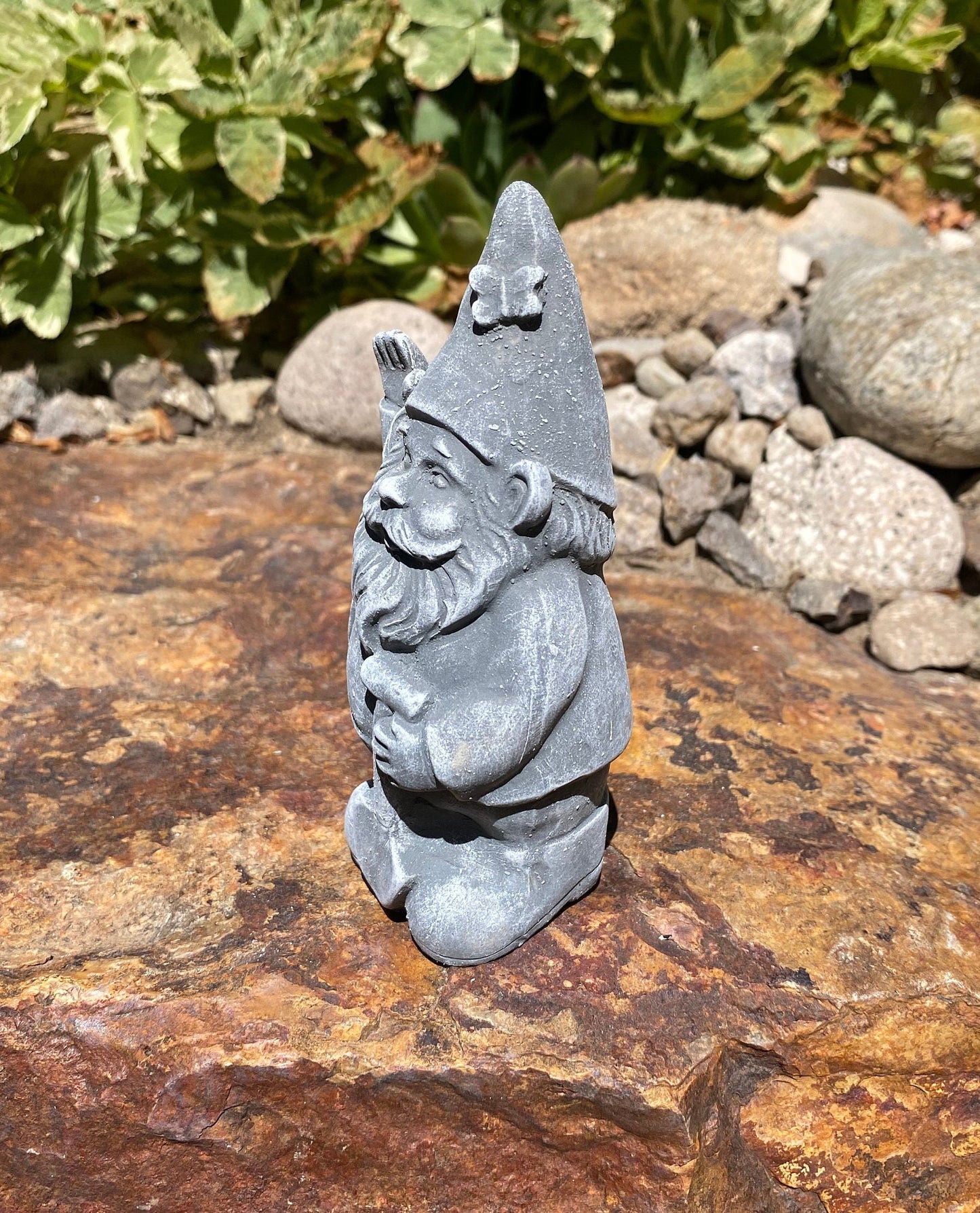 A cute garden gnome holding a shovel, perfect for yard and patio decor