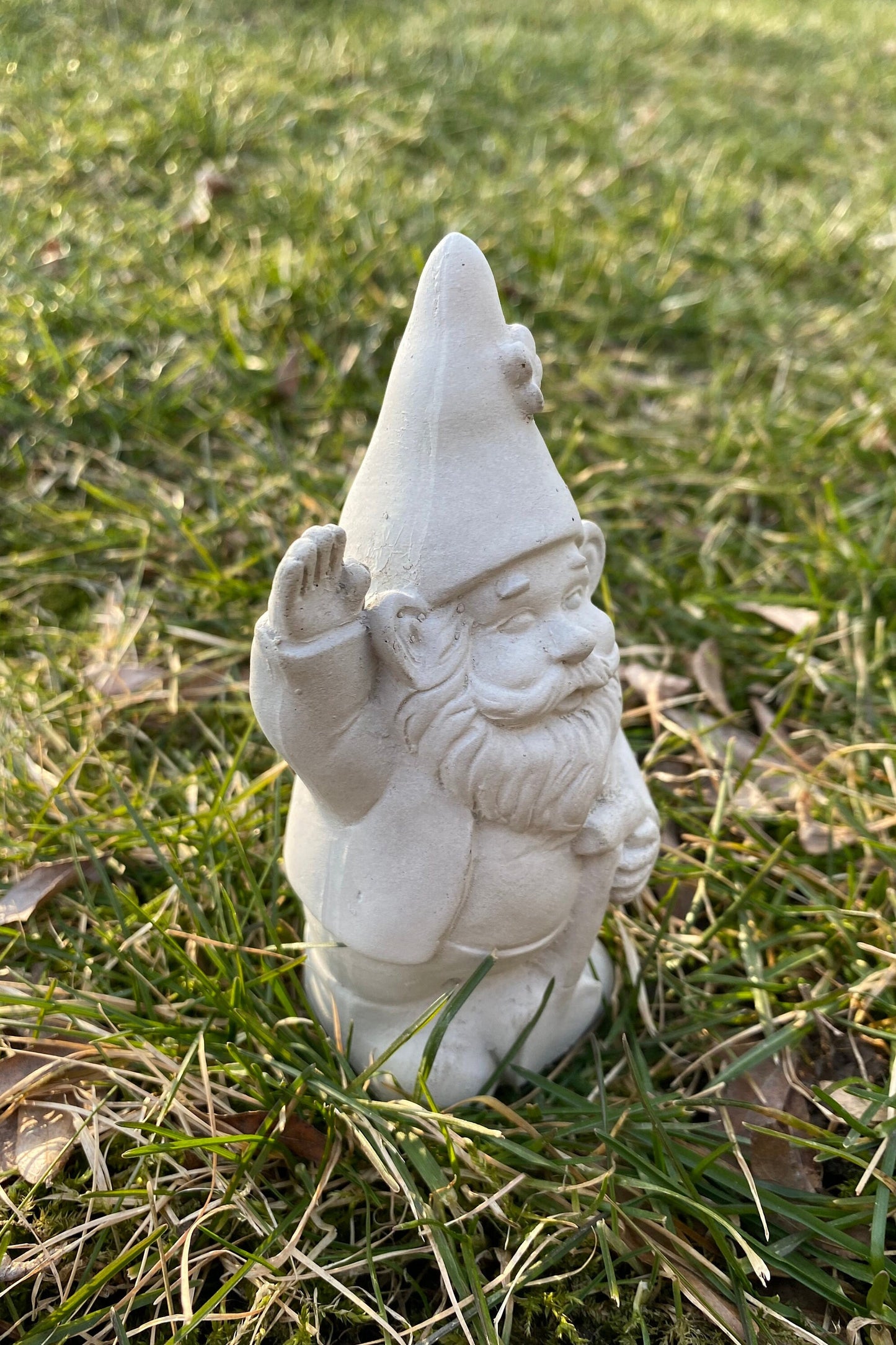 A cute garden gnome holding a shovel, perfect for yard and patio decor