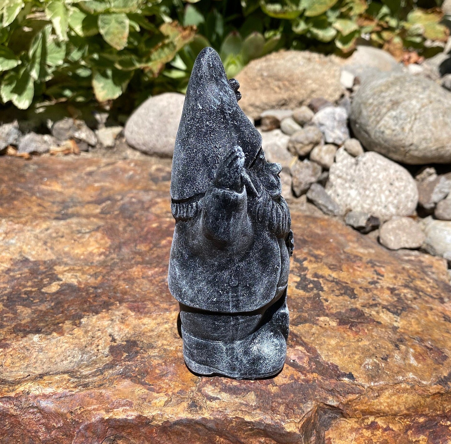A cute garden gnome holding a shovel, perfect for yard and patio decor