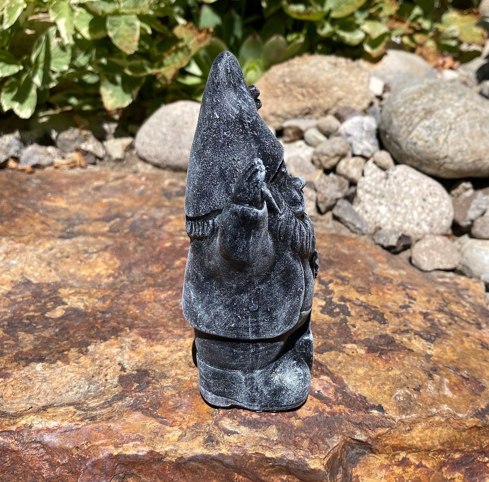 A cute garden gnome holding a shovel, perfect for yard and patio decor